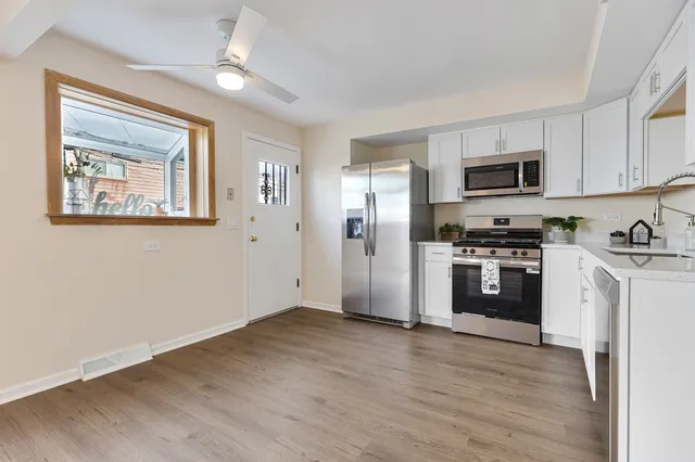 a kitchen with stainless steel appliances granite countertop a refrigerator a stove top oven a sink and dishwasher with wooden floor