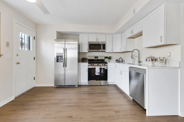 a kitchen with stainless steel appliances granite countertop a refrigerator a stove top oven a sink and dishwasher with wooden floor