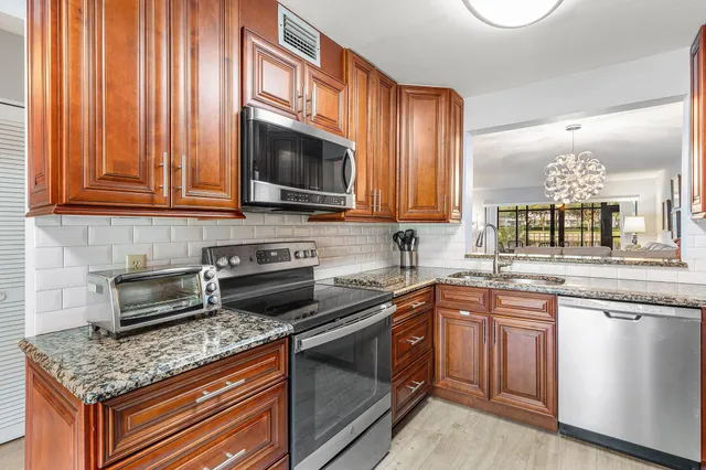a kitchen with stainless steel appliances granite countertop a sink a stove cabinets and a counter top space