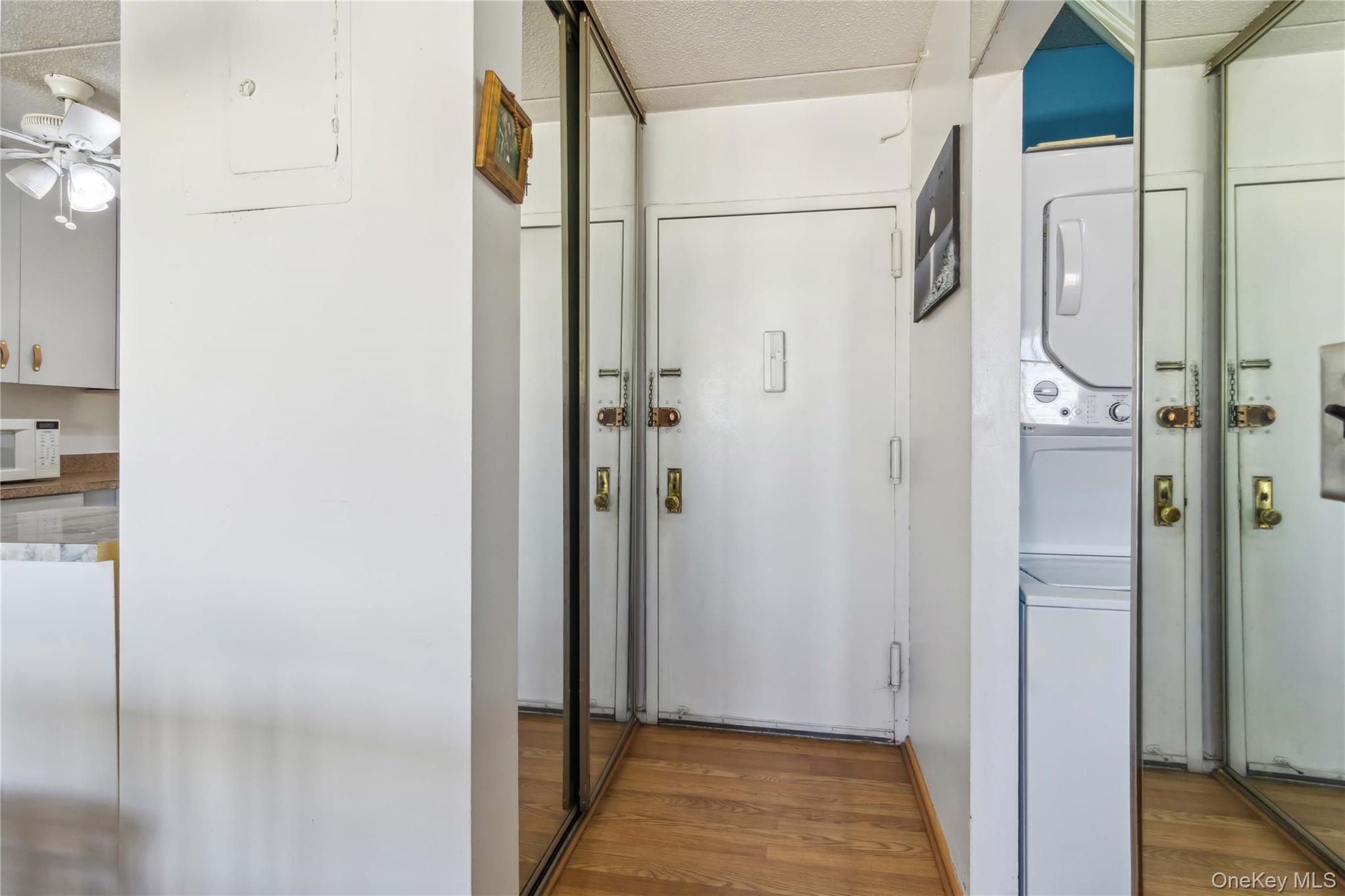 23-22 30th Road, Unit 7D Queens, NY 11102 - Photo 21 of 29 Hallway with stacked washer and dryer, a textured ceiling, and wood finished floors
