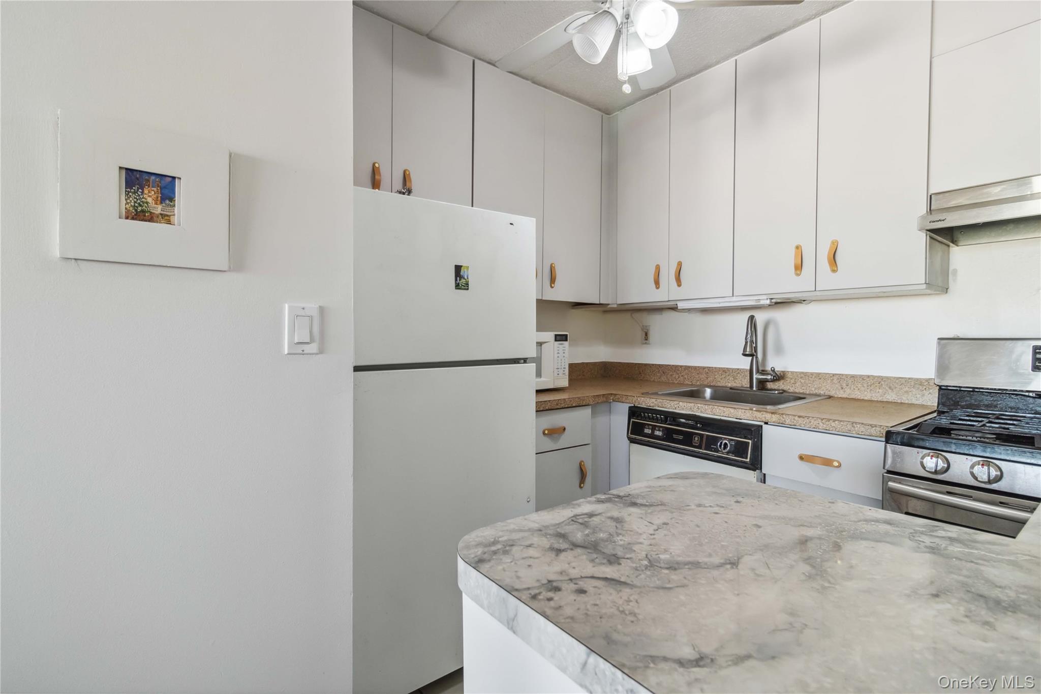 23-22 30th Road, Unit 7D Queens, NY 11102 - Photo 6 of 29 Kitchen featuring white cabinetry, white appliances, a sink, extractor fan, and ceiling fan
