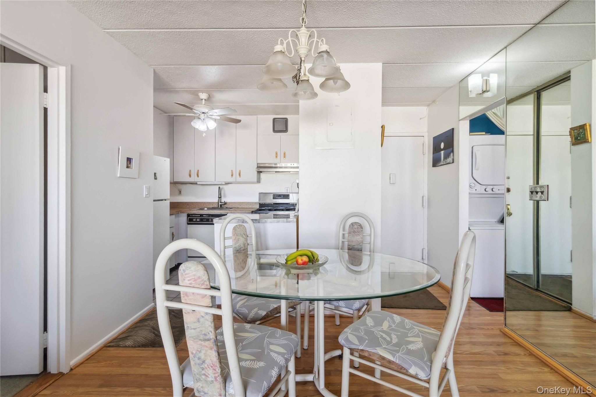 23-22 30th Road, Unit 7D Queens, NY 11102 - Photo 7 of 29 Dining room with ceiling fan with notable chandelier, light wood-type flooring, and stacked washer / dryer