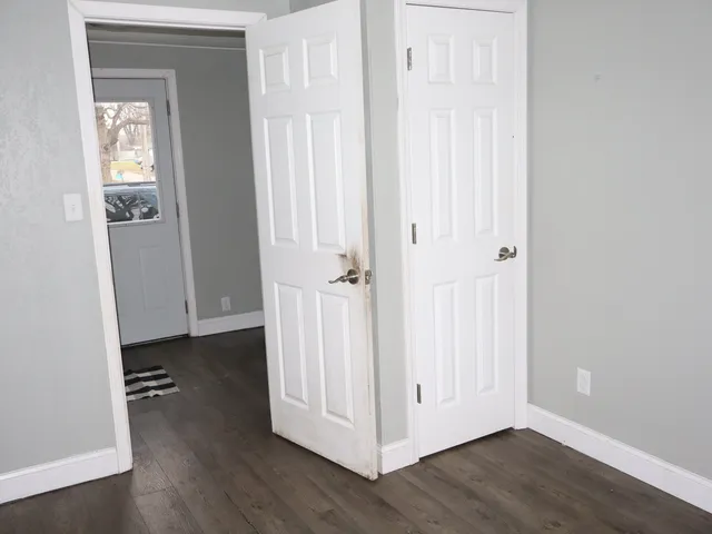 an empty room with wooden floor and closet area