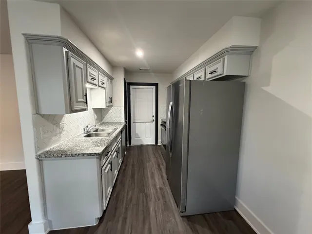a kitchen with granite countertop a refrigerator and a sink