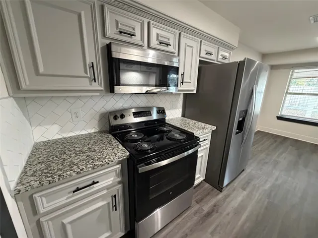 a kitchen with stainless steel appliances granite countertop a stove microwave and refrigerator