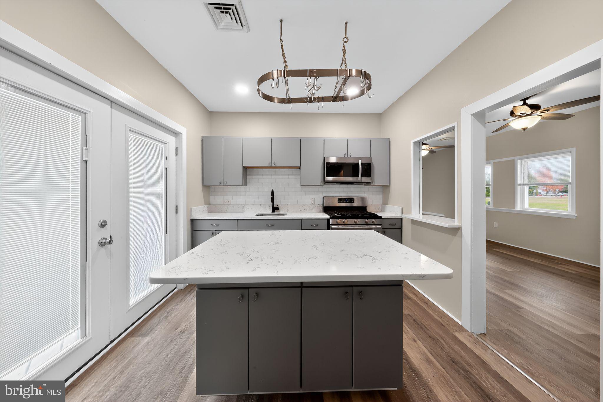 121 Ash Street Carneys Point, NJ 08069 - Photo 11 of 30 a open kitchen with a refrigerator a sink dishwasher a stove and white cabinets with wooden floor