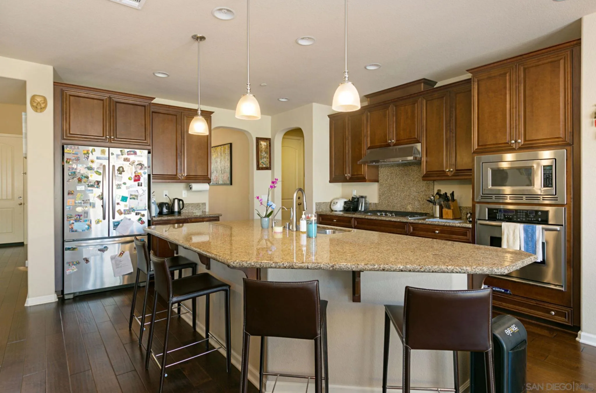 17467 Ralphs Ranch Road San Diego, CA 92127 - Photo 15 of 29 a kitchen with kitchen island granite countertop wooden floor cabinets and a refrigerator
