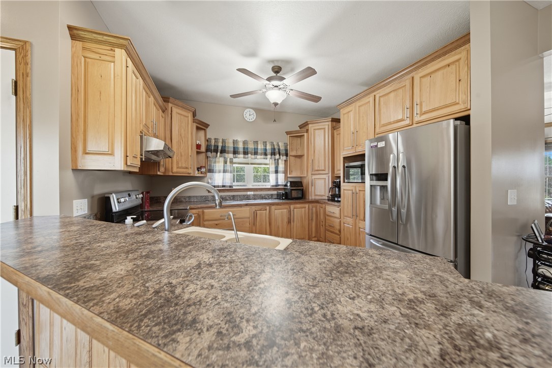 12159 Lawndell Road Southwest Beach City, OH 44608 - Photo 15 of 49 Kitchen featuring wood-finish cabinetry, an integrated stainless steel refrigerator, and a ceiling fan with integrated lighting