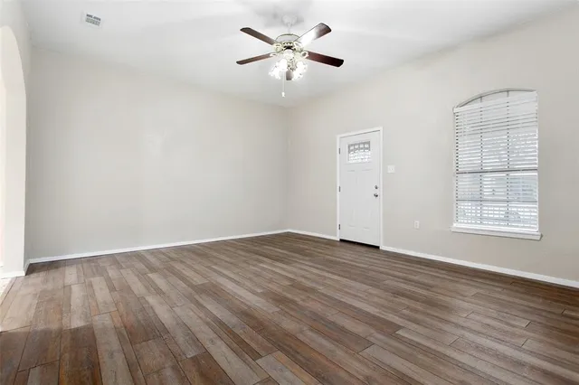 an empty room with wooden floor and windows