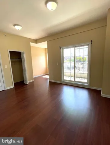 an empty room with wooden floor and windows with curtains