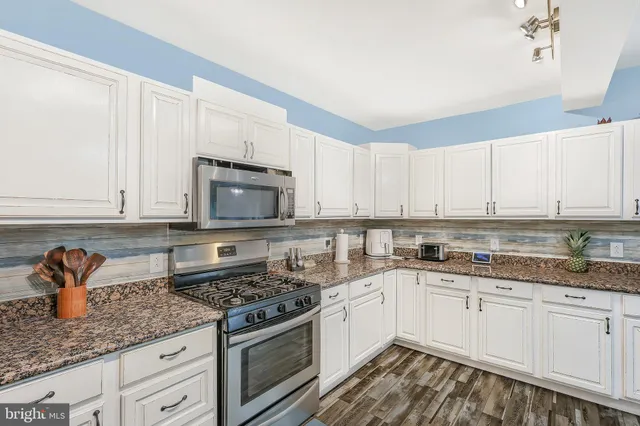 a kitchen with stainless steel appliances granite countertop white cabinets and a stove a oven with white countertops