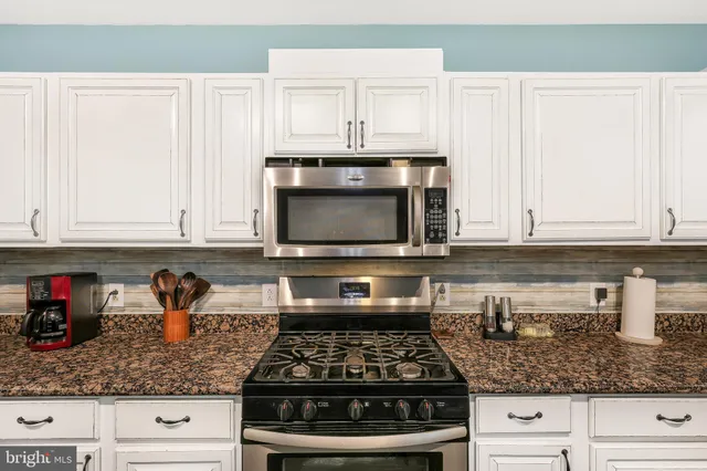 a kitchen with granite countertop white cabinets and stainless steel appliances
