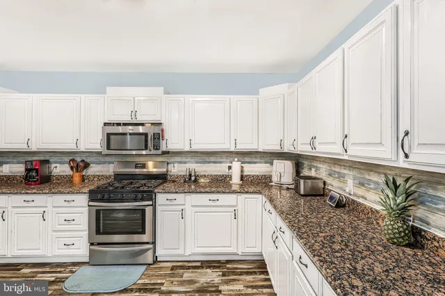 a kitchen with stainless steel appliances granite countertop a sink a stove and cabinets