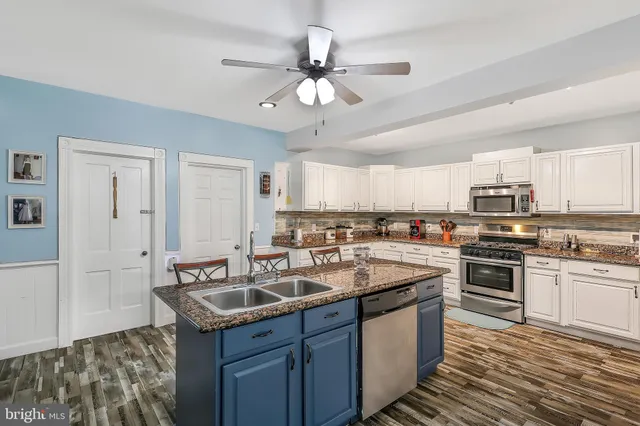 a kitchen with stainless steel appliances granite countertop a stove top oven a sink dishwasher a dining table and chairs with wooden floor