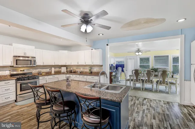 a kitchen with stainless steel appliances granite countertop a sink dishwasher and a stove with wooden floor