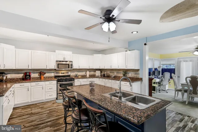 a kitchen with stainless steel appliances kitchen island granite countertop a table chairs and a refrigerator