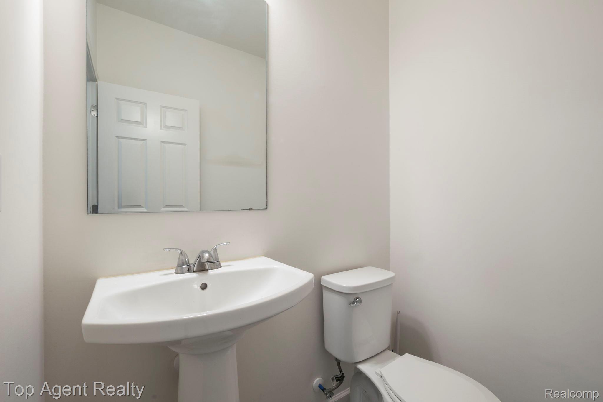 63770 Dequindre Road Washington, MI 48095 - Photo 15 of 61 Pedestal sink with chrome faucet, a wall-mounted mirror, and a white toilet