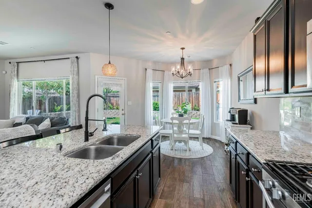 a kitchen with granite countertop a sink a counter space appliances and cabinets