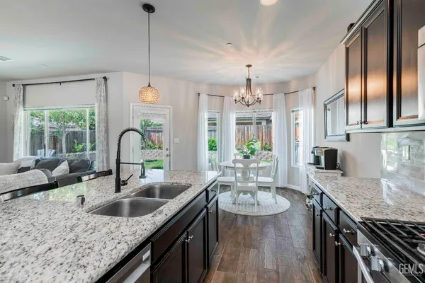 a kitchen with granite countertop a sink a counter space appliances and cabinets