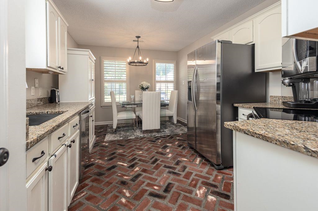 9768 Riggin Drive Memphis, TN 38002 - Photo 6 of 32 Kitchen featuring brick-pattern flooring, white cabinetry with dark hardware, stone-finish countertops, and stainless steel appliances