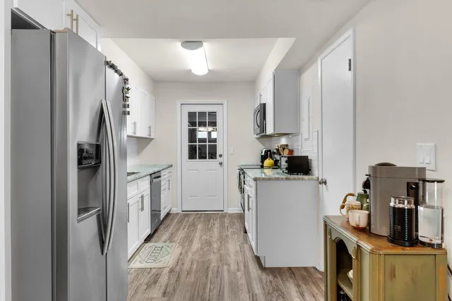 a kitchen with a refrigerator and wooden floor