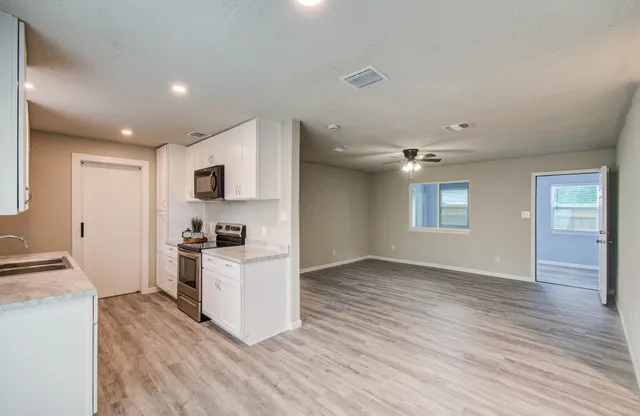 a kitchen with stainless steel appliances granite countertop a stove top oven a sink dishwasher and a refrigerator with wooden floor