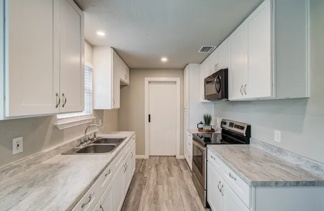 a kitchen with a sink stove top oven and refrigerator
