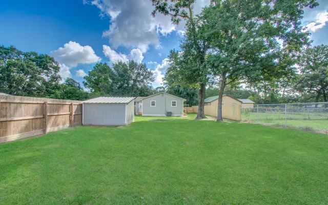 a backyard of a house with table and chairs and a large tree