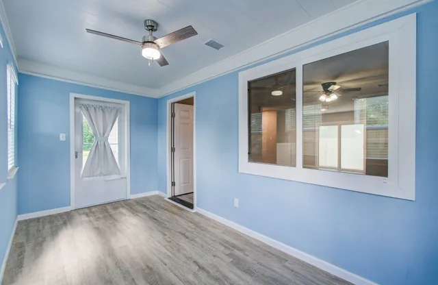 a view of an empty room with a window and wooden floor