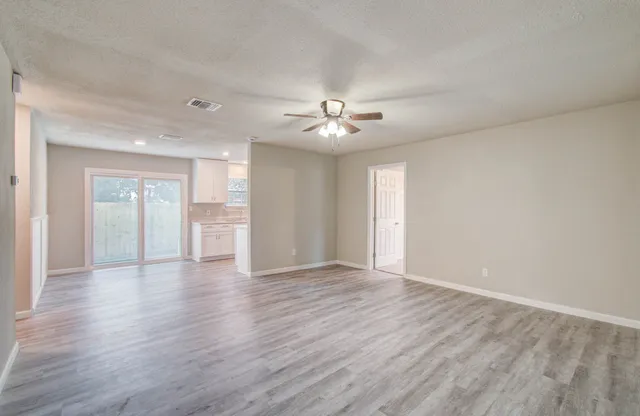 a view of an empty room with a window and wooden floor