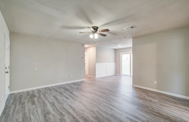 a view of an empty room with a window and wooden floor
