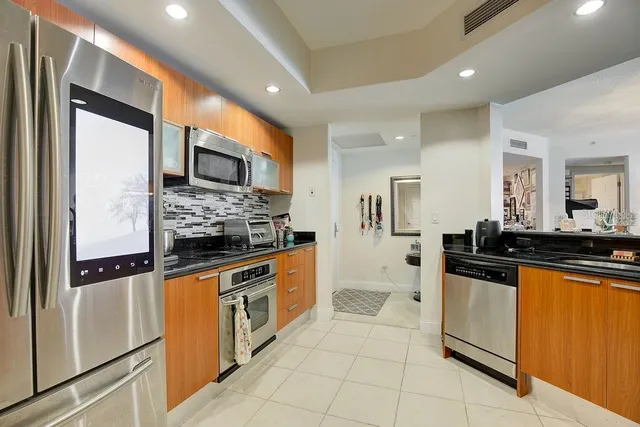 a kitchen with stainless steel appliances granite countertop a refrigerator and a stove top oven