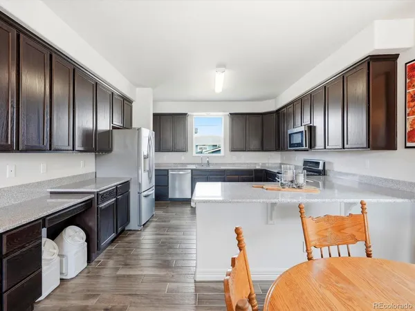 a large kitchen with stainless steel appliances wooden cabinets a stove a sink and a refrigerator