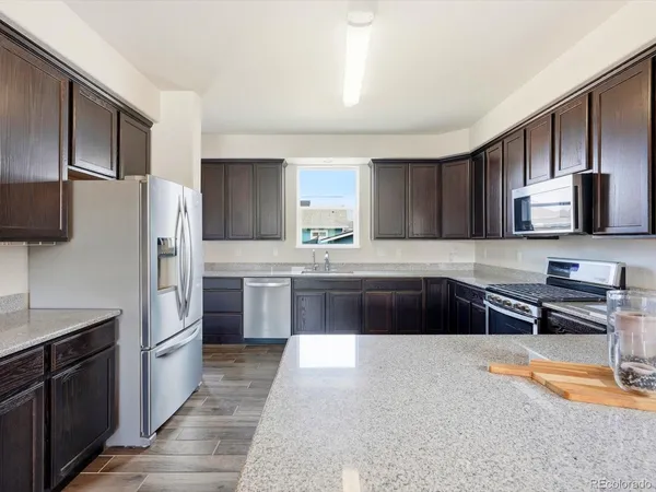 a kitchen with stainless steel appliances granite countertop a refrigerator a stove top oven a sink and dishwasher