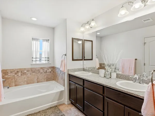 a bathroom with a tub double sink and mirror