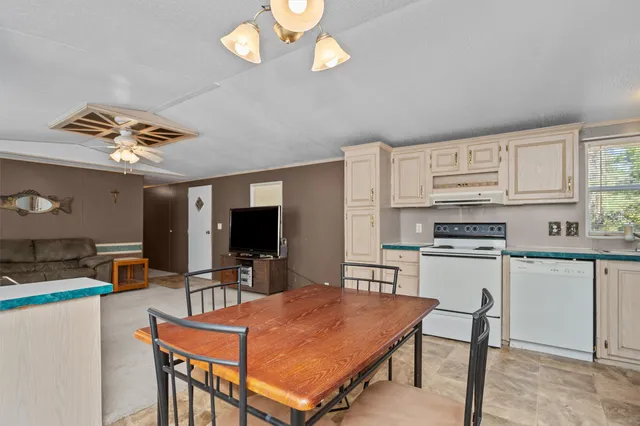 a kitchen with stainless steel appliances granite countertop a stove refrigerator a microwave oven a dining table and chairs with wooden floor