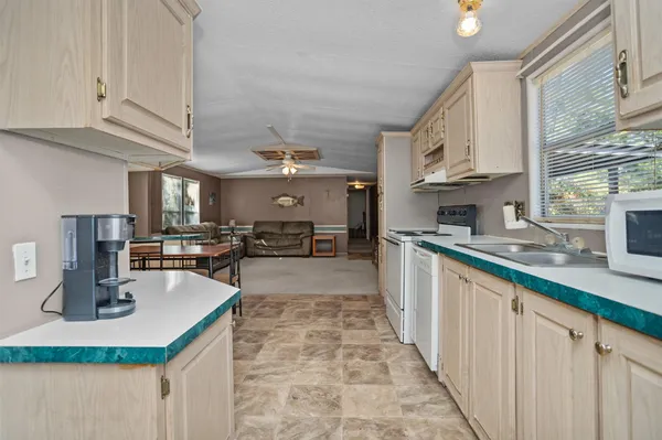 a kitchen with kitchen island granite countertop a sink counter top space cabinets stainless steel appliances and a window