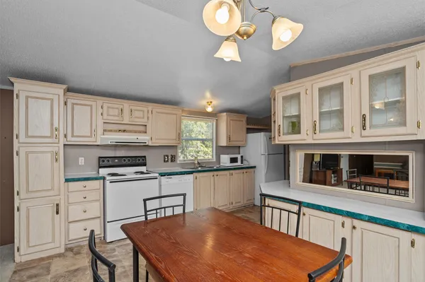 a kitchen with stainless steel appliances granite countertop a stove top oven a sink dishwasher and white cabinets with wooden floor