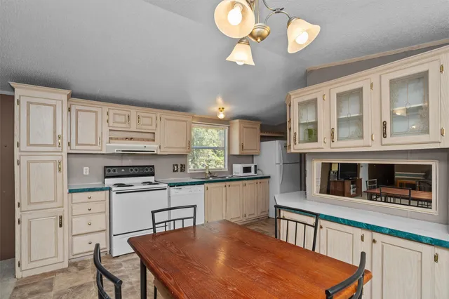 a kitchen with stainless steel appliances granite countertop a stove top oven a sink dishwasher and white cabinets with wooden floor