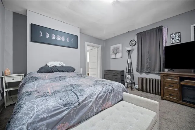 a bedroom with a large bed and a flat tv screen on dresser