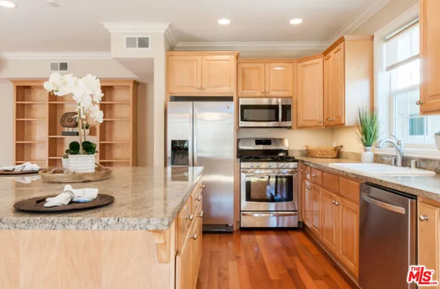 a kitchen with stainless steel appliances kitchen island granite countertop a stove a sink and a refrigerator