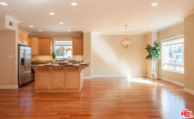 a kitchen with granite countertop a refrigerator a stove a sink cabinets and wooden floor