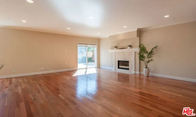 a view of an empty room with wooden floor and a fireplace