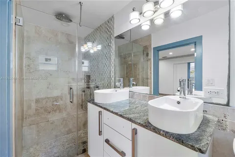 a bathroom with a granite countertop sink a mirror and a shower