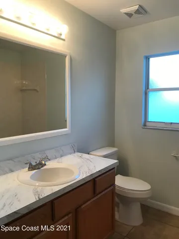 a bathroom with a granite countertop sink a toilet and a mirror