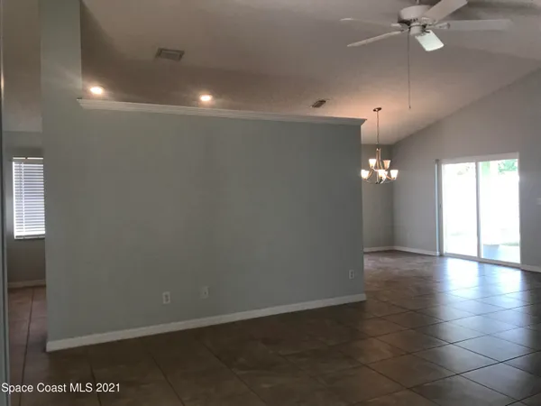 an empty room with wooden floor chandelier fan and windows