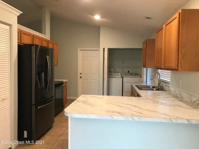 a kitchen with stainless steel appliances kitchen island granite countertop a refrigerator a stove and a sink