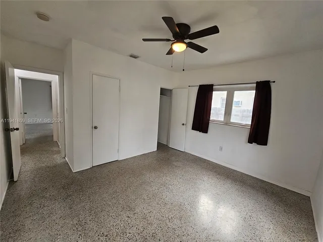 an empty room with windows and fan