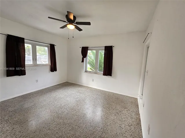 an empty room with ceiling fan and windows