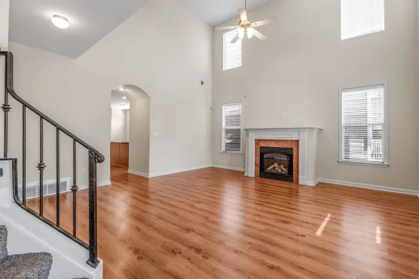 a view of an empty room with wooden floor fireplace and a window